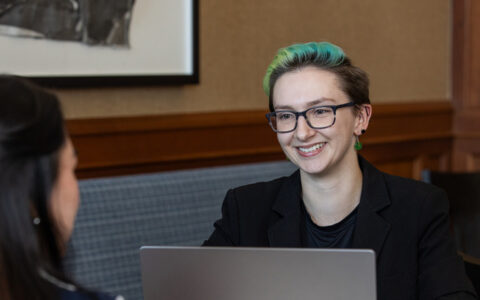 UTulsa MBA candidate smiles during a meeting with a laptop open.