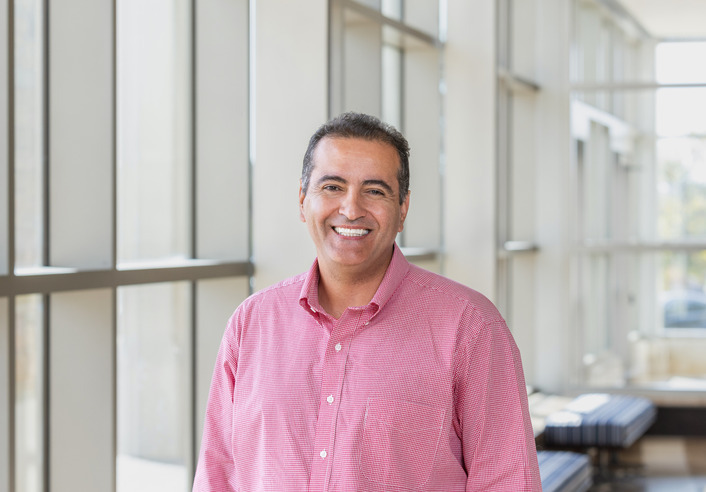 Portrait of a smiling man in a red shirt in a modern building.