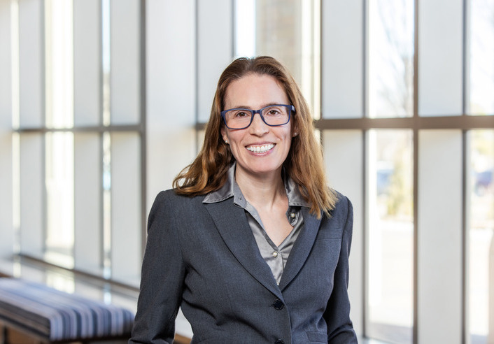 Professional woman in suit, administrative law expert, smiling confidently.