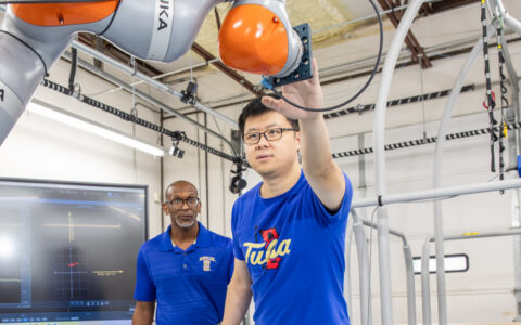UTulsa researchers work with a robotic arm in a lab.