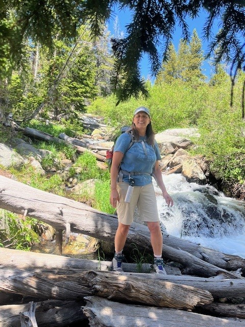 UTulsa kinesiology: Samantha Beams hikes across logs over a stream in a forest.