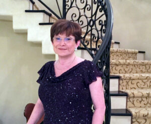 Pat Case, UTulsa supporter, stands elegantly by a staircase.
