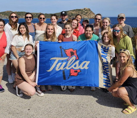 Group poses with Tulsa Hurricane flag on Global Engagement trip.