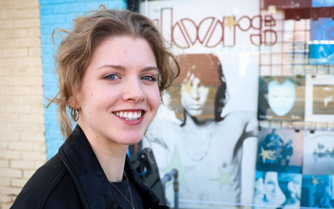 A&S student in front of 101 Archer, with a Tulsa Flyer music poster in the window.