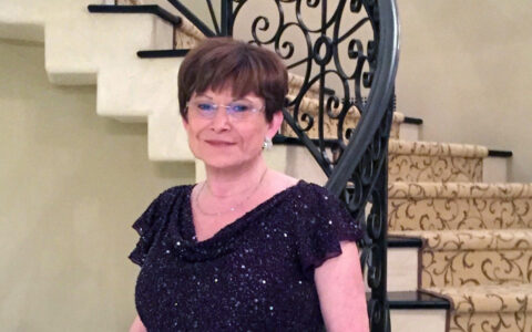 Pat Case, UTulsa supporter, poses in a sequined dress in front of a staircase.