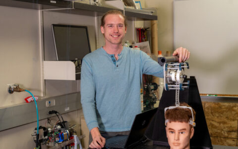 Mechanical engineering student with rehab robotics device and mannequin head.