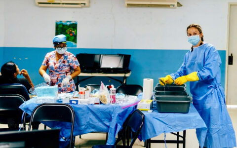 UTulsa pre-health alumni assisting in medical clinic; nurse prepping supplies.