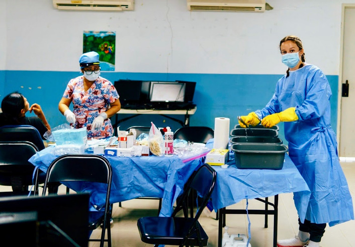 UTulsa pre-health alumni assisting in medical clinic; nurse prepping supplies.