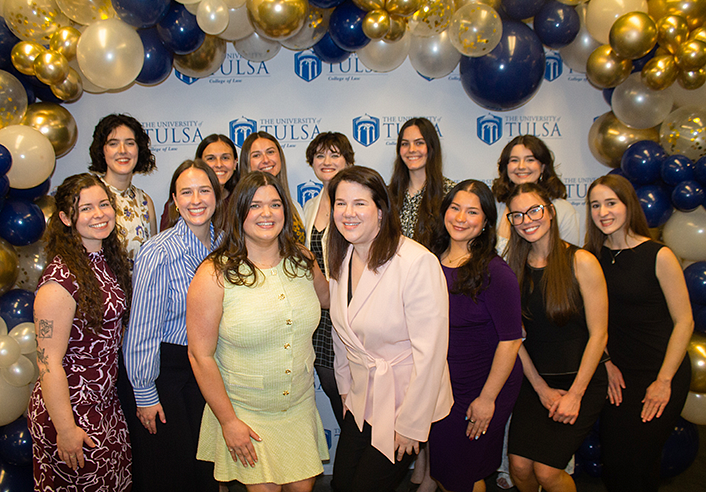 UTulsa Law honors Fern Holland award recipients, posing in front of a University of Tulsa backdrop with gold and blue balloons.