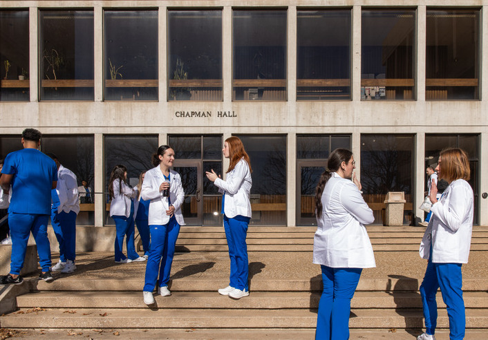 UTulsa nursing students in blue scrubs outside Chapman Hall.