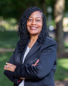 Student Success Coach at UTulsa, smiling with arms crossed in a black blazer. 