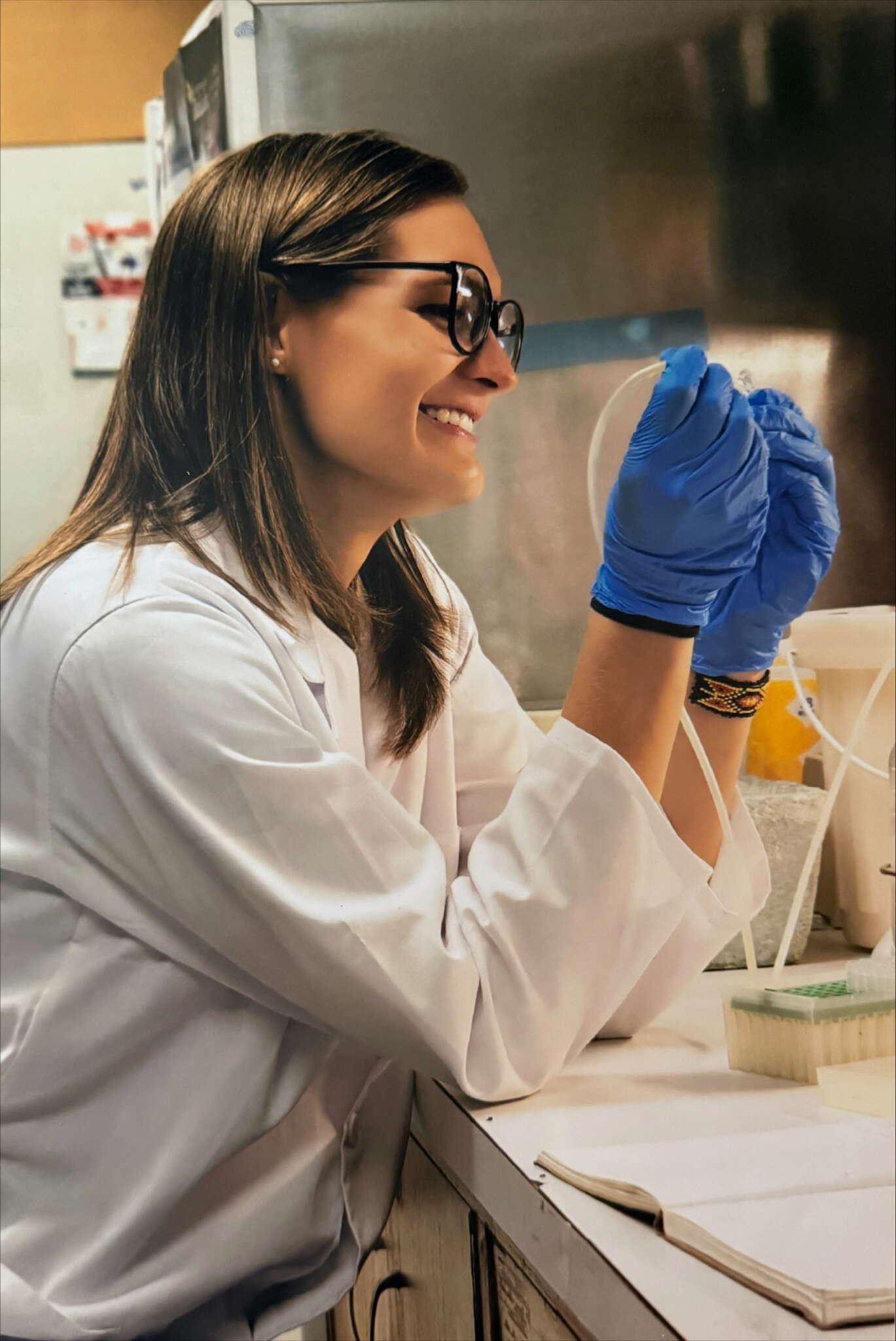 UTulsa transfer student in lab coat smiles while conducting undergraduate research.