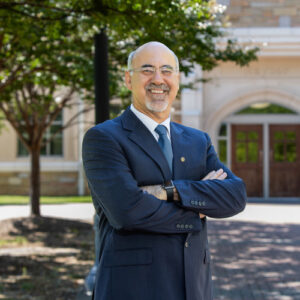 Andreas Polycarpou in suit standing in front of building; College of Engineering & Computer Science.