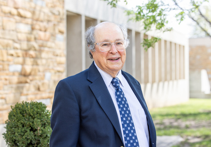 Martin Frey in a suit and tie stands outside a stone building at UTulsa Law.