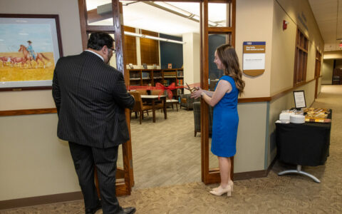 Ribbon cutting ceremony at the Native American Law Center reading room. Sign reads "1303, Native American Law Center.