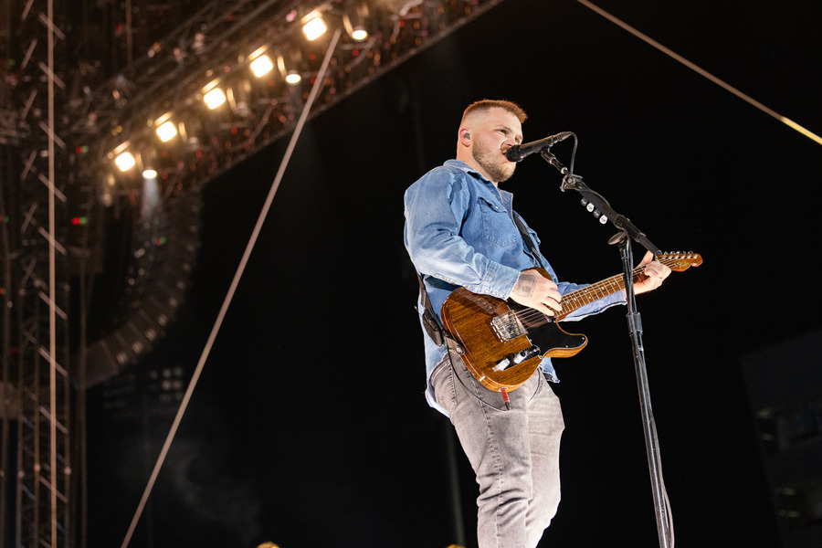 Zach Bryan performing live with his guitar at a 2026 concert.