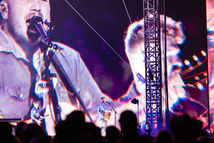 Zach Bryan concert photo: Bryan performing on stage with a large screen behind him.