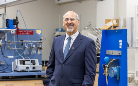 Man in suit in lab, possibly involved in Department of Defense space research or in-space assembly.