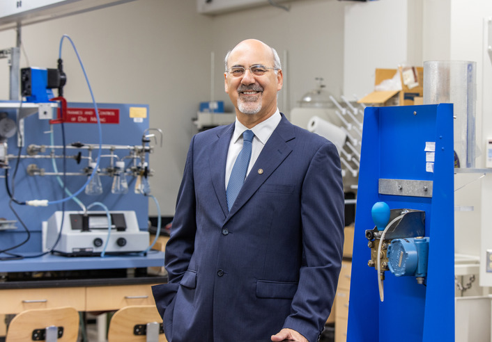 Man in suit in lab, possibly involved in Department of Defense space research or in-space assembly.