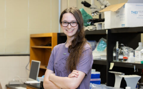 UTulsa's Barry Goldwater Scholarship recipient in a research lab, smiling with arms crossed.