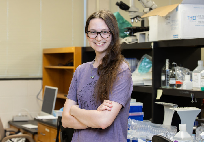 UTulsa's Barry Goldwater Scholarship recipient in a research lab, smiling with arms crossed.