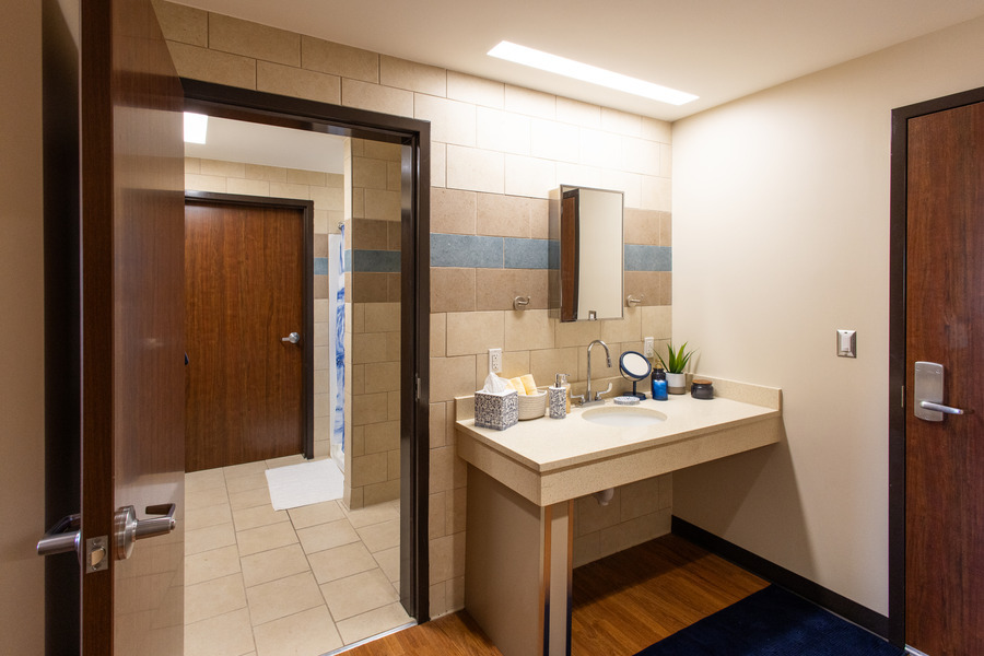 Hardesty Hall bathroom featuring a sink, mirror, and doorway to the shower area.