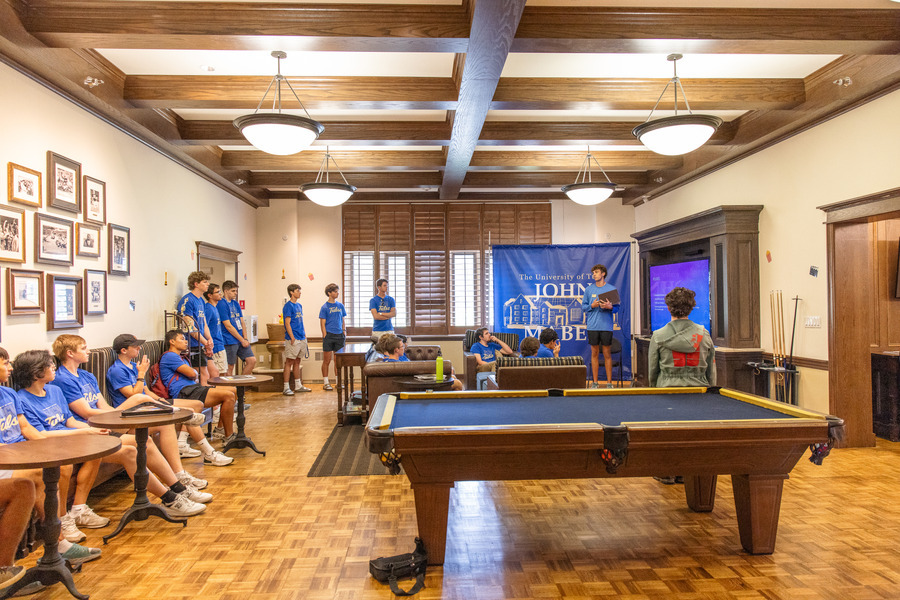 John Mabee Hall: Students gather around a pool table for a presentation.