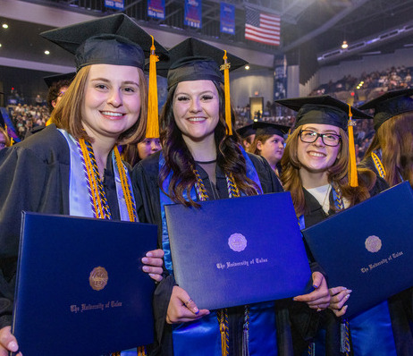 Graduates in caps and gowns hold diplomas from The University of Tulsa.