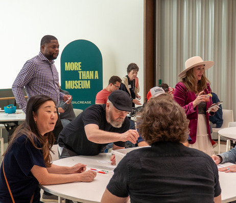 People gathered at a Gilcrease event, with "MORE THAN A MUSEUM" sign in the background