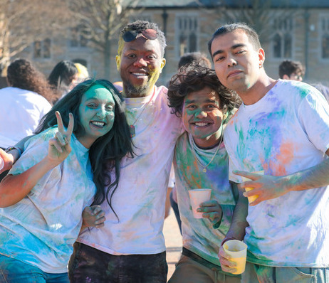 UTulsa students covered in colorful powder celebrate at an outdoor event.