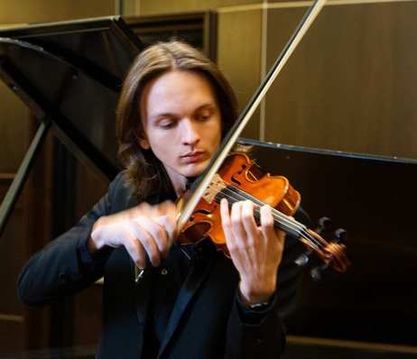 Young man playing the violin at a musical event.