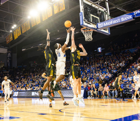 UTulsa basketball players jump for a rebound under the hoop during a game.