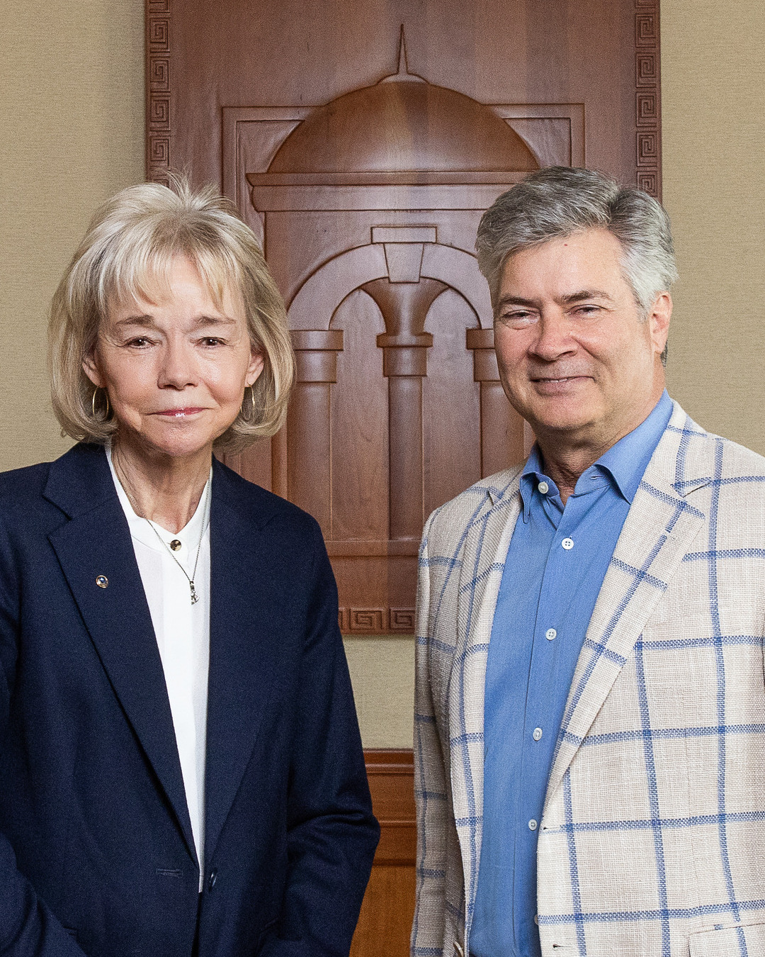 Woman and man standing in front of a wooden carving.