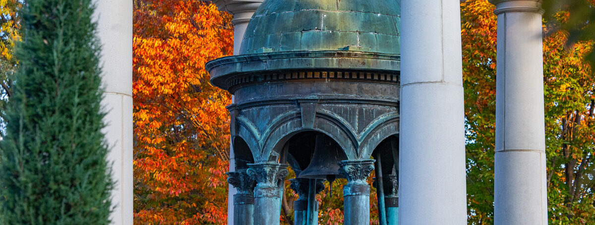 Autumn at a cemetery with a copper-roofed gazebo surrounded by white columns and colorful foliage.