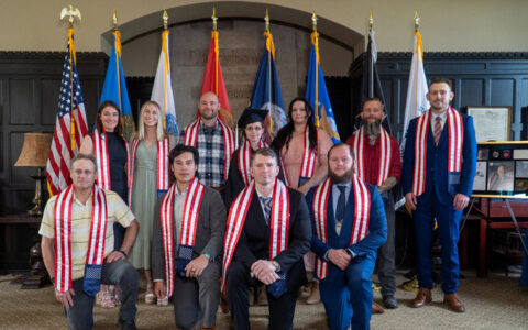 Group of graduates wearing red, white, and blue stoles posing for a photo.