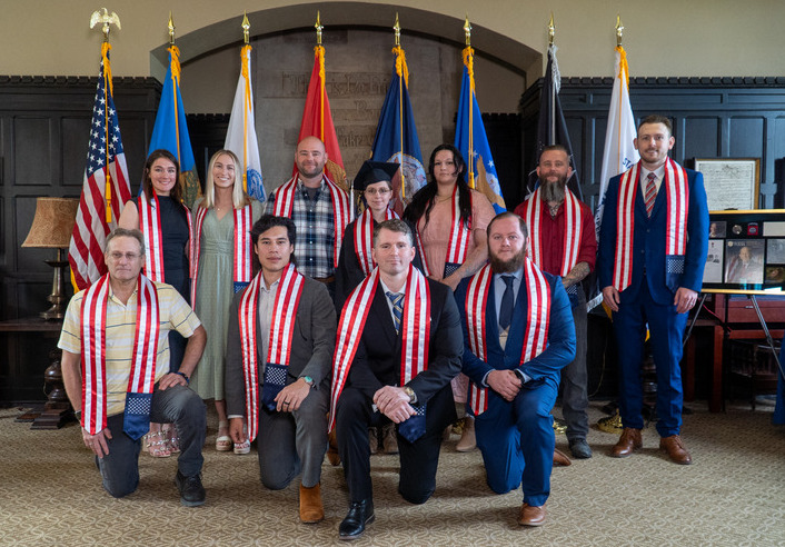 Group of graduates wearing red, white, and blue stoles posing for a photo.