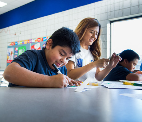 Student drawing with a True blue mentor's help in a classroom.