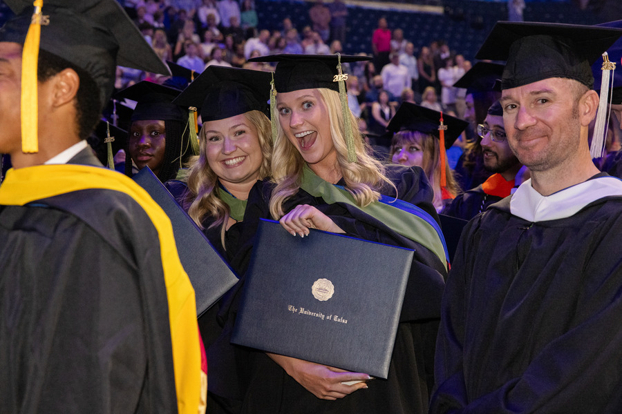 Graduates in caps and gowns hold diplomas at The University of Tulsa commencement.