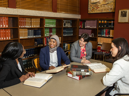 Law students discussing books in the law school library.