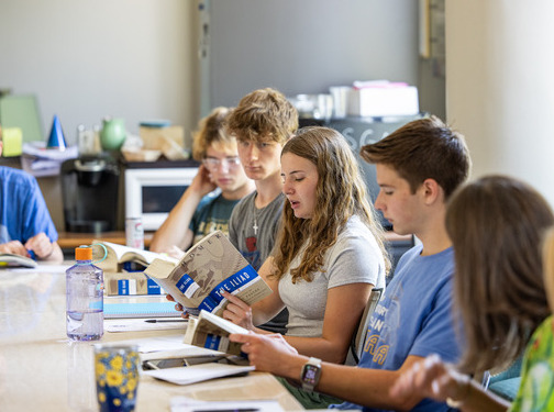 Students in honors class read "The Iliad" in a classroom setting.