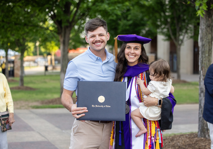 Couple with diploma and baby at 2026 law school hooding ceremony