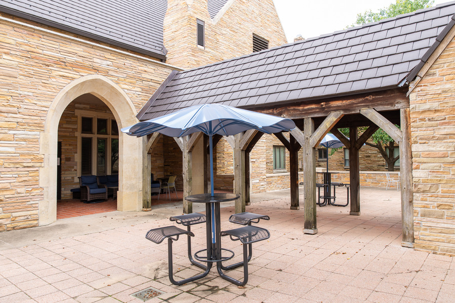 Outdoor seating area with tables and umbrellas at John Mabee Hall