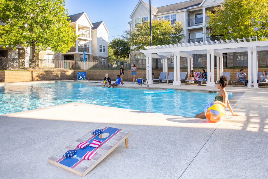 Mayo Village residents relax by the pool with cornhole and beach ball