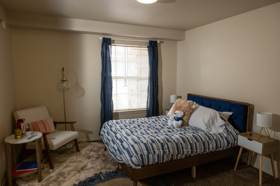 Mayo Village bedroom with blue and white bedding, armchair, and window.