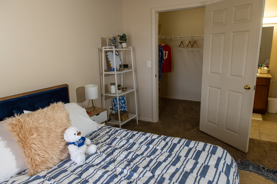 Mayo Village bedroom with a bed, shelf, and open closet.