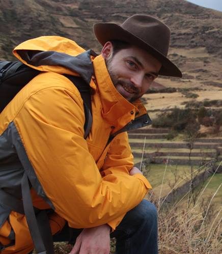 Philip Tinker, alumnus, smiling in a yellow raincoat at an outdoor location