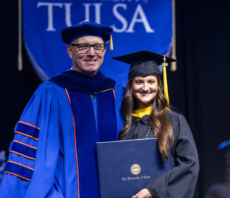 University of Tulsa commencement: graduate with diploma and professor in academic regalia.