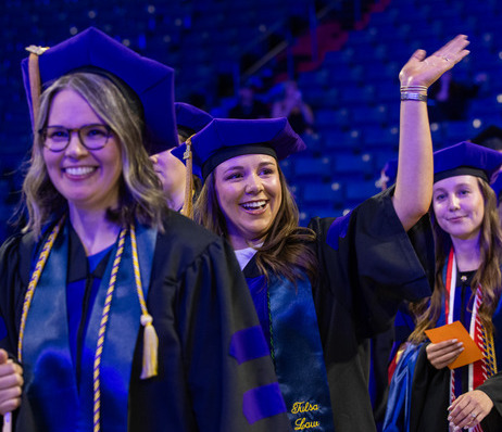 Law graduates in regalia at commencement 2026, one waving.