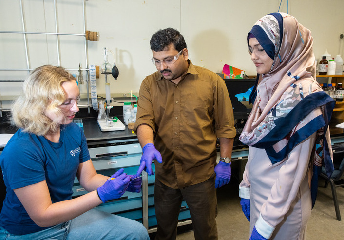 Chemistry student researchers examining a sample in a science lab