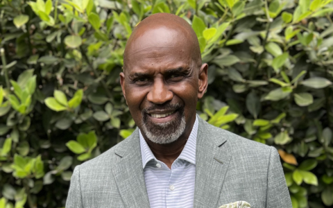 Julius Tennon, UTulsa's 2026 commencement speaker, smiles in a suit.
